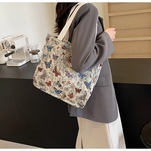 Close-up of oversized canvas tote bag with colorful butterfly prints and woven strap