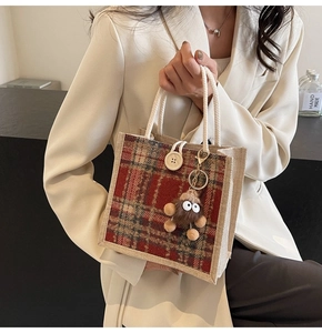 Close-up of linen tote with red plaid wool patchwork, wooden button, and plush pendant