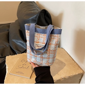 Close-up of blue and orange plaid linen bucket bag with woven handles and brand label