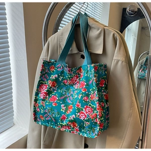 Detail of floral tote bag with red roses on dark cyan canvas and green handles