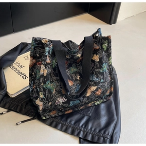 Detail of butterfly pattern tote bag with wide handles on a stylish leather jacket
