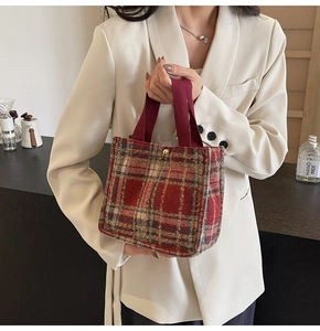 Close-up of red plaid tweed handbag with woven handles and golden snap button closure