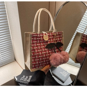 Detail of tweed woven lunch bag with large wooden button and cute cherry plush pendant