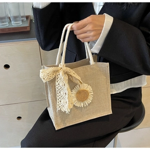 Detail of jute tote bag featuring white rope handles and decorative lace bow with sun flower