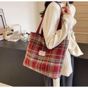 Détail du cabas en tweed à carreaux marron-rouge avec bandoulière et anses tissées