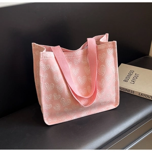 Detail view of pink canvas tote bag with white heart pattern and ribbon handles