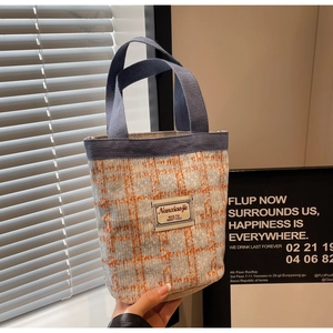Close-up of woven tweed bucket bag in blue and orange with durable canvas handle