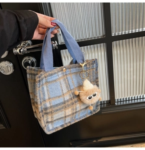 Detail of blue and brown plaid tweed tote bag with a fun fuzzy monster charm