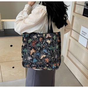 Detail of jacquard tote bag featuring colorful butterfly patterns and sturdy black handles