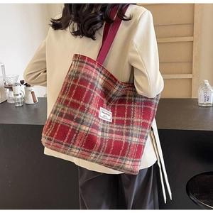 Détail du grand sac cabas à carreaux rouge-brun en tweed porté à l'épaule par un mannequin