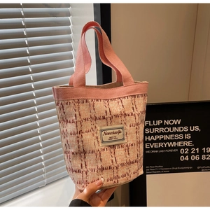 Close-up of pink and white tweed tote bag featuring woven fabric and a brand textile label