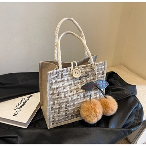 Détail du sac cabas en tweed tissé avec anses en corde, bouton en bois et breloque cerise