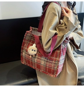 Red and grey plaid woolen tote bag with a white plush doll charm and burgundy straps