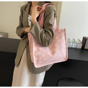 Detail of pink canvas tote bag featuring white heart grid patterns and woven shoulder strap
