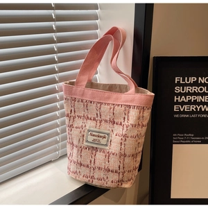 Pink plaid tweed tote bag detail with white woven brand label and textured fabric surface