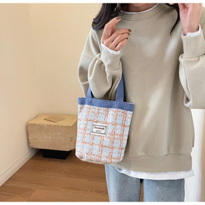 Detail of blue and orange tweed bucket bag with woven texture and white fabric label