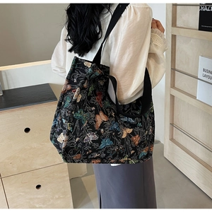 Detail of a large canvas tote bag featuring an artistic butterfly jacquard pattern and strap