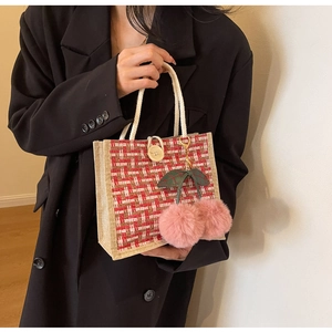 Detailed view of linen weave lunch bag with red plaid and pink cherry pom pom charm