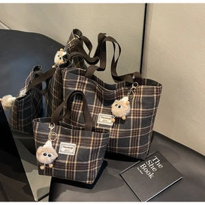 Detail of grey plaid canvas tote bag set with plush sheep charms and brown straps