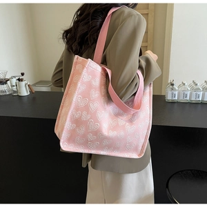 Detailed view of pink canvas tote bag with white heart embroidery and woven straps