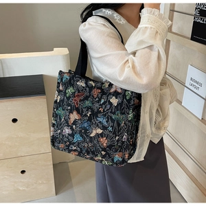 Model wearing a black jacquard tote bag with colorful butterfly embroidery patterns