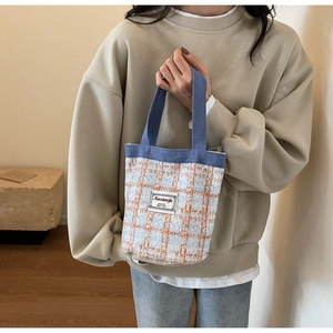 Detail of blue and orange checkered fabric texture and brand label on a small tote bag