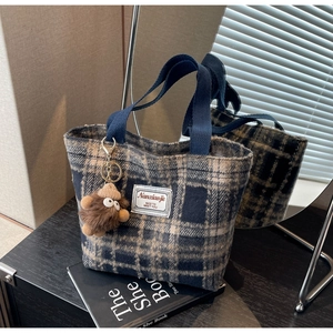 Détail du sac cabas en laine à carreaux avec charm de monstre en peluche marron