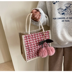 Side view of linen lunch bag featuring red plaid fabric and pink cherry plush charms