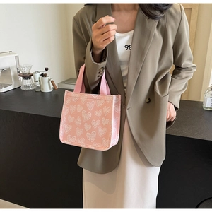 Detailed shot of pink canvas tote bag with white heart patterns and fabric handle