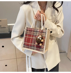 Detail of linen tote bag with red plaid pattern and brown plush monster charm