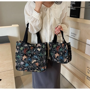 Detail view of colorful butterfly embroidery on black canvas tote bags in two sizes