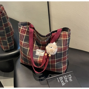 Close-up of red and grey checkered canvas tote bag with a cute beige plush charm