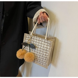 Detail of linen woven tote with brown grid pattern and large plush cherry charm