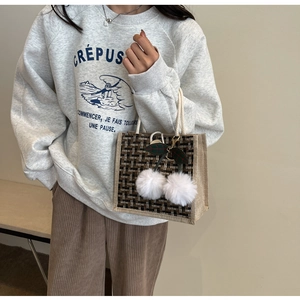 Détail du sac à lunch en lin tissé avec motif à carreaux et breloques cerises en pompon
