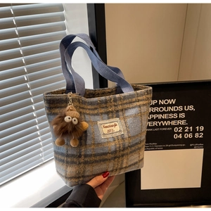 Détail d'un sac cabas en tweed à carreaux avec anse tissée bleue et charm monstre