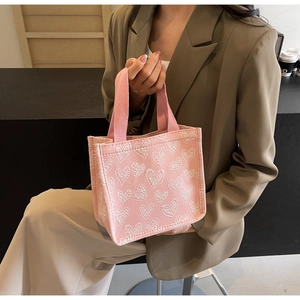Detailed shot of pink canvas tote bag with white heart patterns and woven handles