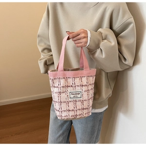 Detail of pink and white checkered tweed tote bag with woven texture and canvas handle