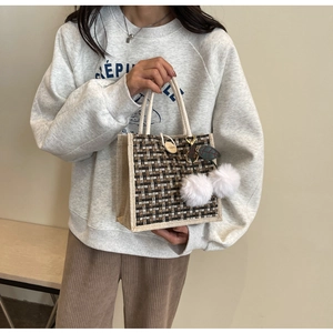 Détail du sac à lunch en lin avec texture tissée et breloques pompons blancs doux