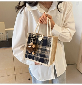 Detail of checkered linen handbag with plush monster charm and rope handles
