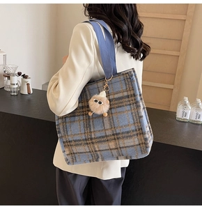 Detail of blue plaid tote bag with wide shoulder strap and cute plush charm pendant