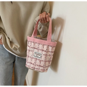 Detail view of a pink and white tweed mini bucket bag with soft canvas handles