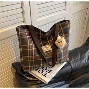 Detailed view of checkered tote bag with plush charm and woven shoulder strap