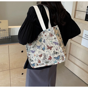 Close-up of beige tote bag with butterfly prints and thick cotton straps