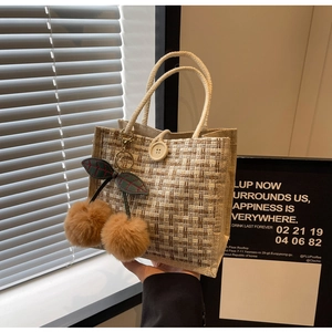 Detail of woven linen lunch bag with rope handle and cherry plush charms decoration