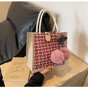 Detailed shot of beige linen tote bag with red gingham trim and cherry pompom charm