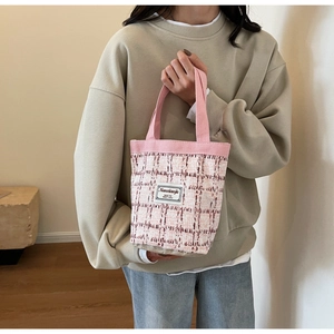 Detail of pink tweed bucket bag featuring woven texture and branded fabric label