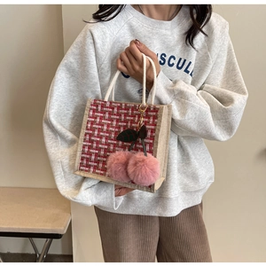 Detailed shot of woven plaid lunch bag featuring a pink pom-pom cherry accessory