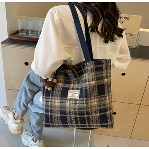 Détail du sac cabas à carreaux avec breloque monstre et étiquette en tissu sur l'épaule