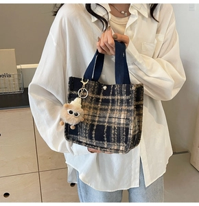 Detail of plaid tweed tote bag with navy straps and beige plush doll keychain