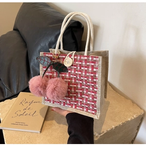 Detail of tweed linen tote bag featuring a plush cherry charm and rustic wooden button